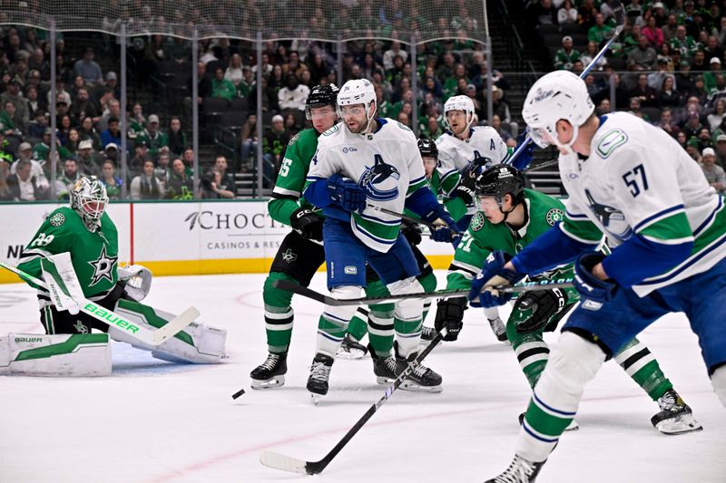 Jan 31, 2025; Dallas, Texas, USA; Vancouver Canucks defenseman Tyler Myers (57) attempts a shot past left wing Jake DeBrusk (74) and Dallas Stars left wing Jason Robertson (21) and defenseman Thomas Harley (55) and goaltender Jake Oettinger (29) during the first period at the American Airlines Center. Mandatory Credit: Jerome Miron-Imagn Images