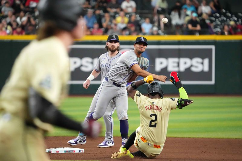 Aug 13, 2024; Phoenix, Arizona, USA; Colorado Rockies shortstop Ezequiel Tovar (14) throws to first base for a double play against Arizona Diamondbacks outfielder Jake McCarthy (31) after forcing out Arizona Diamondbacks shortstop Geraldo Perdomo (2) at second during the seventh inning at Chase Field. Mandatory Credit: Joe Camporeale-USA TODAY Sports