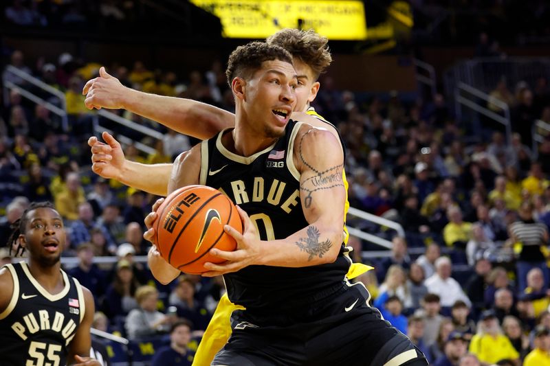 Feb 25, 2024; Ann Arbor, Michigan, USA;  Purdue Boilermakers forward Mason Gillis (0) grabs rebound over Michigan Wolverines forward Will Tschetter (42) in the first half at Crisler Center. Mandatory Credit: Rick Osentoski-USA TODAY Sports