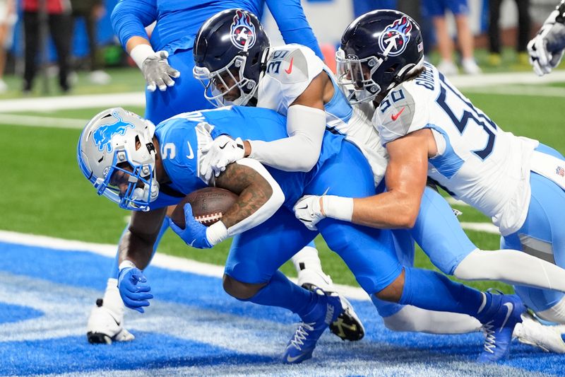 Detroit Lions running back David Montgomery (5) runs into the end zone for a touchdown past Tennessee Titans cornerback Darrell Baker Jr. (39) and linebacker Jack Gibbens (50) during the first half of an NFL football game Sunday, Oct. 27, 2024, in Detroit. (AP Photo/Paul Sancya)