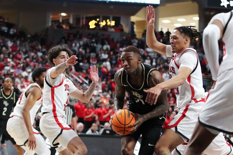 Feb 10, 2024; Lubbock, Texas, USA; Central Florida Knights forward CJ Walker (21) drives between Texas Tech Red Raiders guards Pop Isaacs (2) and Darrion Williams (5) in the first half United Supermarkets Arena. Mandatory Credit: Michael C. Johnson-USA TODAY Sports