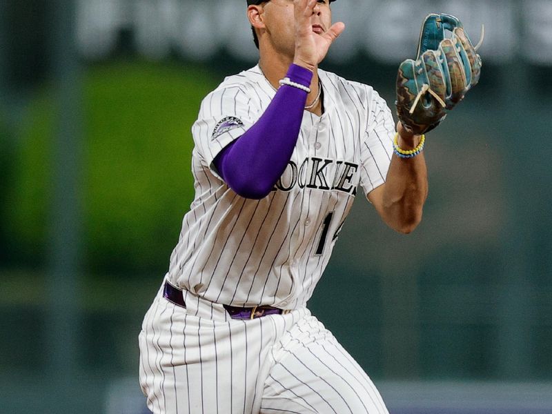 Apr 9, 2025; Denver, Colorado, USA; Colorado Rockies shortstop Ezequiel Tovar (14) bobbles the ball on a fielding play in the fifth inning against the Milwaukee Brewers at Coors Field. Mandatory Credit: Isaiah J. Downing-Imagn Images