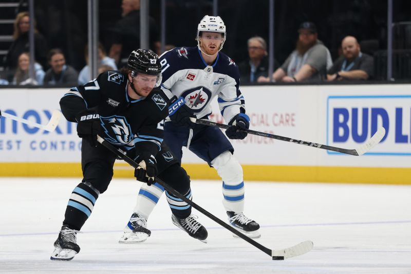 Dec 21, 2025; Salt Lake City, Utah, USA; Utah Mammoth center Barrett Hayton (27) skates with the puck against Winnipeg Jets left wing Kyle Connor (81) during the first period at Delta Center. Mandatory Credit: Rob Gray-Imagn Images