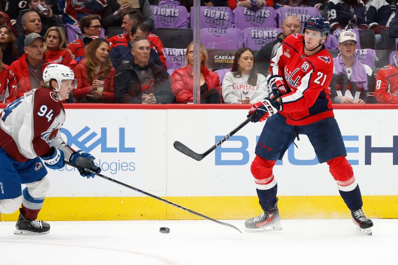 Nov 21, 2024; Washington, District of Columbia, USA; Washington Capitals center Aliaksei Protas (21) passes the puck as Colorado Avalanche left wing Joel Kiviranta (94) defends in the first period at Capital One Arena. Mandatory Credit: Geoff Burke-Imagn Images