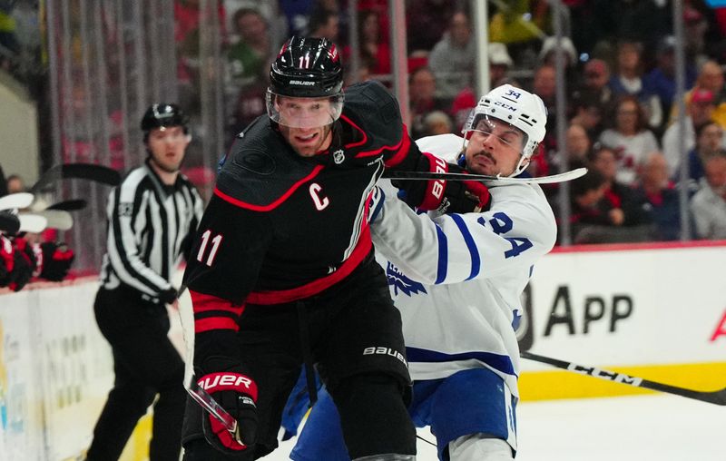 Mar 24, 2024; Raleigh, North Carolina, USA;  Carolina Hurricanes center Jordan Staal (11) and Toronto Maple Leafs center Auston Matthews (34) battle for position during the third period at PNC Arena. Mandatory Credit: James Guillory-USA TODAY Sports