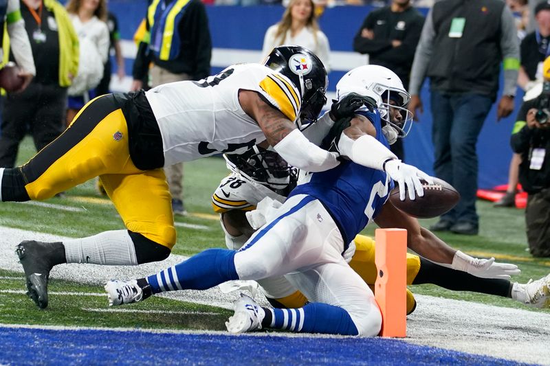 Indianapolis Colts running back Zack Moss, right, scores with Pittsburgh Steelers linebacker Mykal Walker, rear, and Pittsburgh Steelers linebacker Elandon Roberts, left, defending during the first half of an NFL football game in Indianapolis Saturday, Dec. 16, 2023. (AP Photo/Michael Conroy)