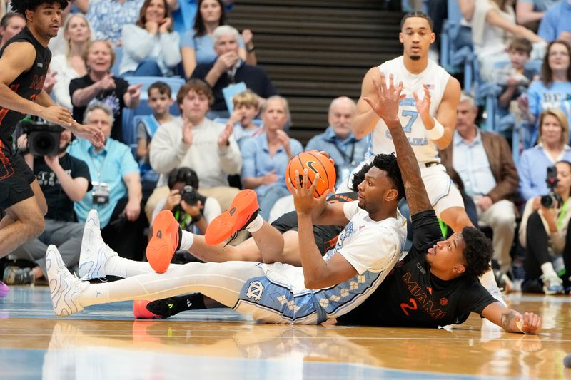 Mar 1, 2025; Chapel Hill, North Carolina, USA;  North Carolina Tar Heels forward Jalen Washington (13) with the ball as Miami (Fl) Hurricanes forward Brandon Johnson (2) defends in the first half at Dean E. Smith Center. Mandatory Credit: Bob Donnan-Imagn Images