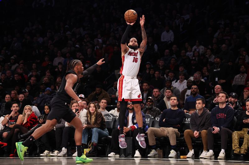 NEW YORK, NEW YORK - JANUARY 15:  Caleb Martin #16 of the Miami Heat shoots against Dennis Smith Jr. #4 of the Brooklyn Nets during their game at Barclays Center on January 15, 2024 in New York City.   User expressly acknowledges and agrees that, by downloading and or using this photograph, User is consenting to the terms and conditions of the Getty Images License Agreement.  (Photo by Al Bello/Getty Images)