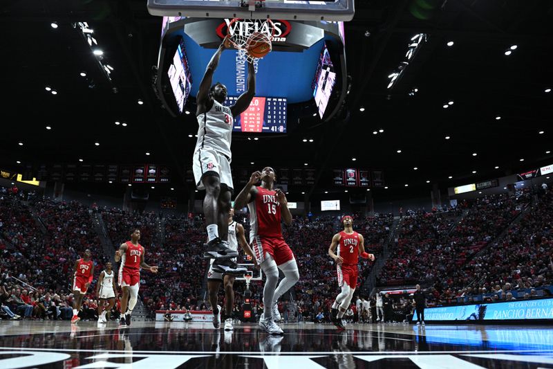 Feb 11, 2023; San Diego, California, USA; San Diego State Aztecs forward Nathan Mensah (31) dunks the ball ahead of UNLV Rebels guard Luis Rodriguez (15) during the first half at Viejas Arena. Mandatory Credit: Orlando Ramirez-USA TODAY Sports