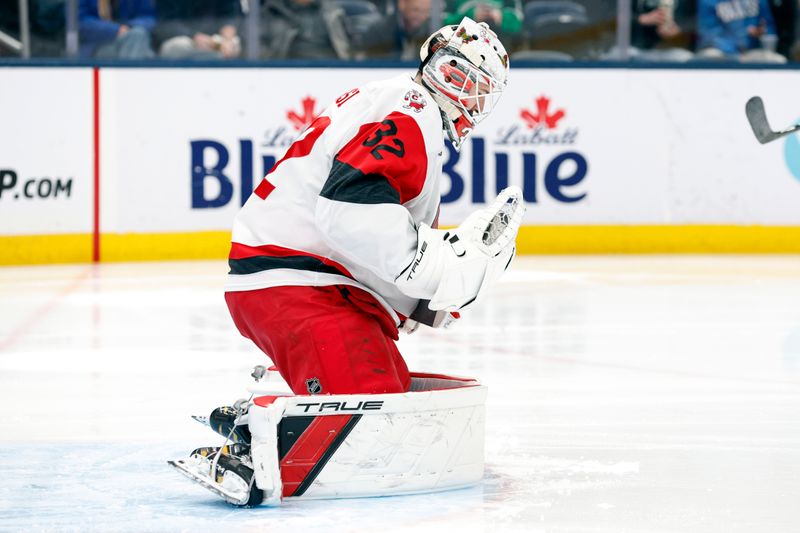 Mar 17, 2026; Columbus, Ohio, USA; Carolina Hurricanes goalie Brandon Bussi (32) makes a glove save against the Columbus Blue Jackets during the second period at Nationwide Arena. Mandatory Credit: Russell LaBounty-Imagn Images