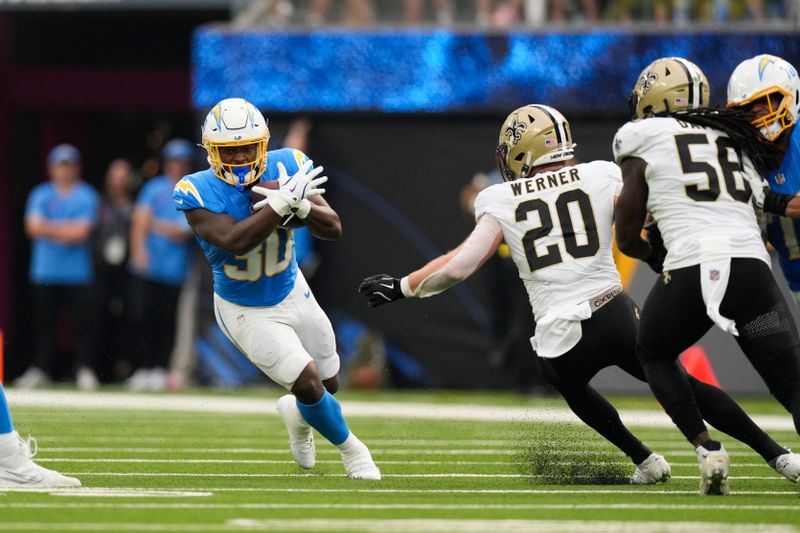 Los Angeles Chargers running back Kimani Vidal (30) carries past New Orleans Saints linebacker Pete Werner (20) and linebacker Demario Davis (56) in the first half of an NFL football game in Inglewood, Calif., Sunday, Oct. 27, 2024. (AP Photo/Mark J. Terrill)