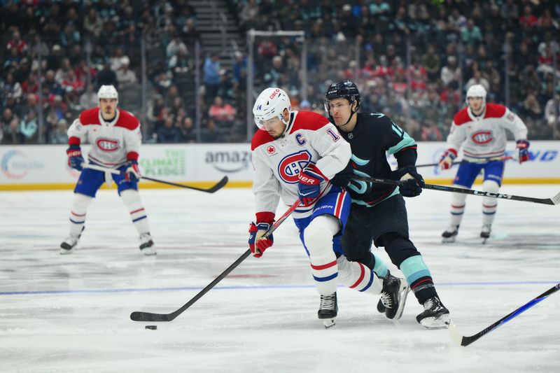 Oct 28, 2025; Seattle, Washington, USA; Montreal Canadiens center Nick Suzuki (14) plays the puck while defended by Seattle Kraken left wing Tye Kartye (12) during the second period at Climate Pledge Arena. Mandatory Credit: Steven Bisig-Imagn Images