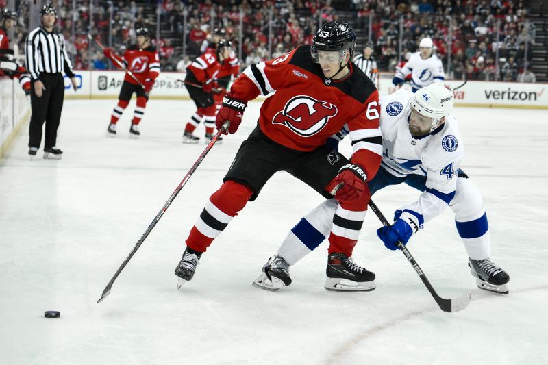 Feb 25, 2024; Newark, New Jersey, USA; New Jersey Devils left wing Jesper Bratt (63) skates with the puck while being defended by Tampa Bay Lightning defenseman Calvin de Haan (44) during the second period at Prudential Center. Mandatory Credit: John Jones-USA TODAY Sports