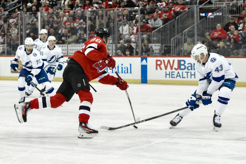 Feb 25, 2024; Newark, New Jersey, USA; New Jersey Devils center Jack Hughes (86) shoots the puck while being defended by Tampa Bay Lightning defenseman Darren Raddysh (43) during the second period at Prudential Center. Mandatory Credit: John Jones-USA TODAY Sports