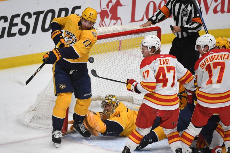 Jan 4, 2024; Nashville, Tennessee, USA; Nashville Predators center Yakov Trenin (13) and Calgary Flames center Connor Zary (47) play the puck out of the air after a save by goaltender Juuse Saros (74) during the first period at Bridgestone Arena. Mandatory Credit: Christopher Hanewinckel-USA TODAY Sports