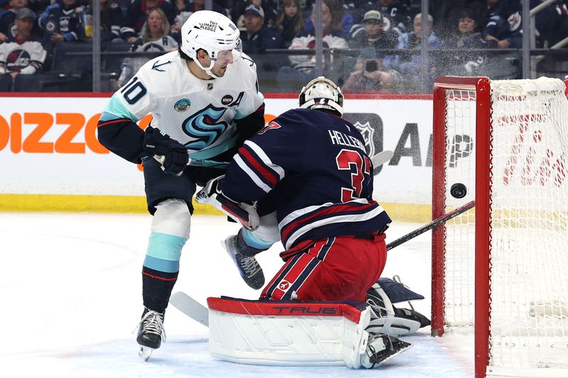Jan 16, 2025; Winnipeg, Manitoba, CAN; Seattle Kraken center Matty Beniers (10) scores on Winnipeg Jets goaltender Connor Hellebuyck (37) in the first period at Canada Life Centre. Mandatory Credit: James Carey Lauder-Imagn Images