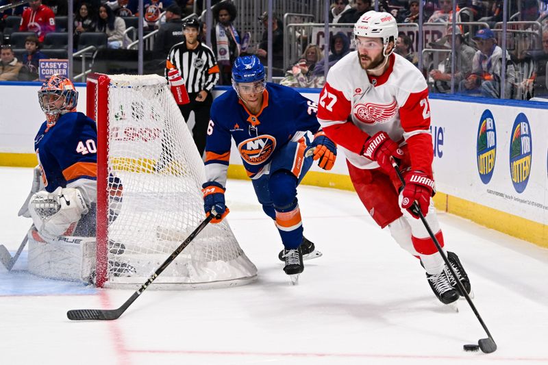 Nov 25, 2024; Elmont, New York, USA;  Detroit Red Wings center Michael Rasmussen (27) skates the puck from behind the net chased by New York Islanders defenseman Ryan Pulock (6) during the second period at UBS Arena. Mandatory Credit: Dennis Schneidler-Imagn Images