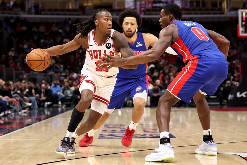 CHICAGO, ILLINOIS - FEBRUARY 12: Ayo Dosunmu #11 of the Chicago Bulls dribbles the ball as Jalen Duren #0 and Cade Cunningham #2 of the Detroit Pistons defend during the first quarter at the United Center on February 12, 2025 in Chicago, Illinois. NOTE TO USER: User expressly acknowledges and agrees that, by downloading and or using this photograph, user is consenting to the terms and conditions of the Getty Images License Agreement.  (Photo by Luke Hales/Getty Images)