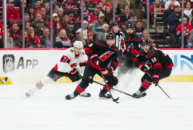 Nov 16, 2024; Raleigh, North Carolina, USA;  Carolina Hurricanes center Jack Drury (18) skates with the puck along with  left wing Eric Robinson (50) against Ottawa Senators center Ridly Greig (71) during the first period at Lenovo Center. Mandatory Credit: James Guillory-Imagn Images