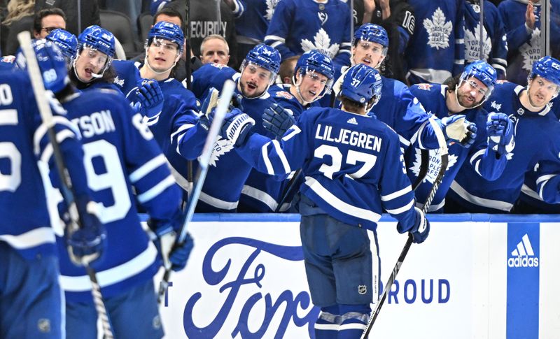 Dec 30, 2023; Toronto, Ontario, CAN; Toronto Maple Leafs defenseman Timothy Liljegren (37) celebrates with team mates at the bench after scoring against the Carolina Hurricanes in the third period at Scotiabank Arena. Mandatory Credit: Dan Hamilton-USA TODAY Sports