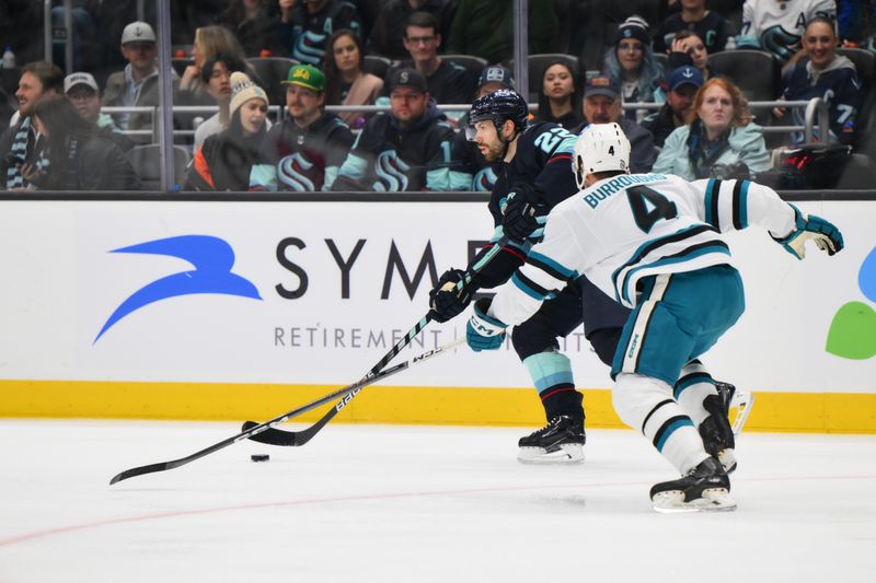 Nov 22, 2023; Seattle, Washington, USA; Seattle Kraken right wing Oliver Bjorkstrand (22) plays the puck while defended by San Jose Sharks defenseman Kyle Burroughs (4) during the second period at Climate Pledge Arena. Mandatory Credit: Steven Bisig-USA TODAY Sports