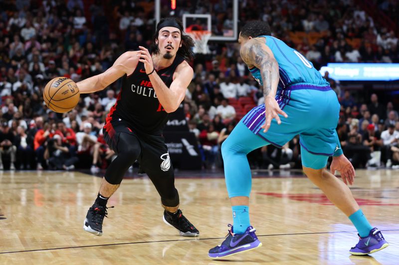 MIAMI, FLORIDA - JANUARY 14: Jaime Jaquez Jr. #11 of the Miami Heat drives against Miles Bridges #0 the Charlotte Hornets during the second quarter at Kaseya Center on January 14, 2024 in Miami, Florida. NOTE TO USER: User expressly acknowledges and agrees that, by downloading and or using this photograph, User is consenting to the terms and conditions of the Getty Images License Agreement.  (Photo by Megan Briggs/Getty Images)