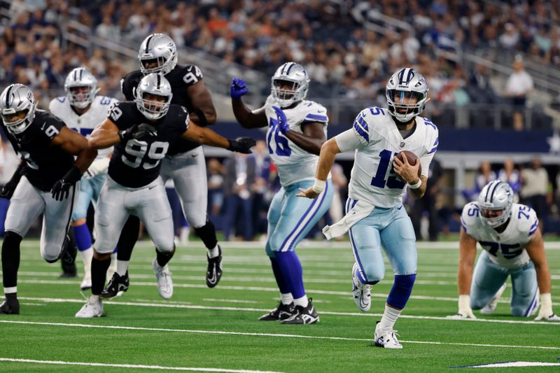 Dallas Cowboys quarterback Will Grier (15) keeps the ball for a gain as Las Vegas Raiders defensive end Jordan Willis (99) and others give chase in the first half of a preseason NFL football game in Arlington, Texas, Saturday, Aug. 26, 2023. (AP Photo/Michael Ainsworth)