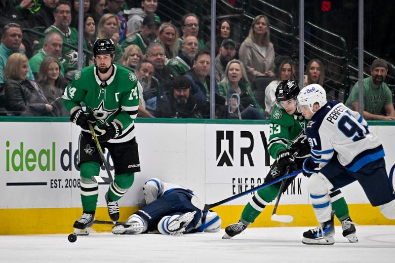 Apr 10, 2025; Dallas, Texas, USA; Dallas Stars left wing Jamie Benn (14) stands over Winnipeg Jets center Vladislav Namestnikov (7) after a check as center Wyatt Johnston (53) and center Cole Perfetti (91) battle for the puck during the first period at the American Airlines Center. Mandatory Credit: Jerome Miron-Imagn Images