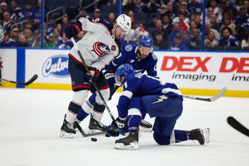 Mar 4, 2025; Tampa, Florida, USA; Columbus Blue Jackets center Adam Fantilli (19) and Tampa Bay Lightning center Zemgus Girgensons (28) battle for the puck in the third period at Amalie Arena. Mandatory Credit: Nathan Ray Seebeck-Imagn Images