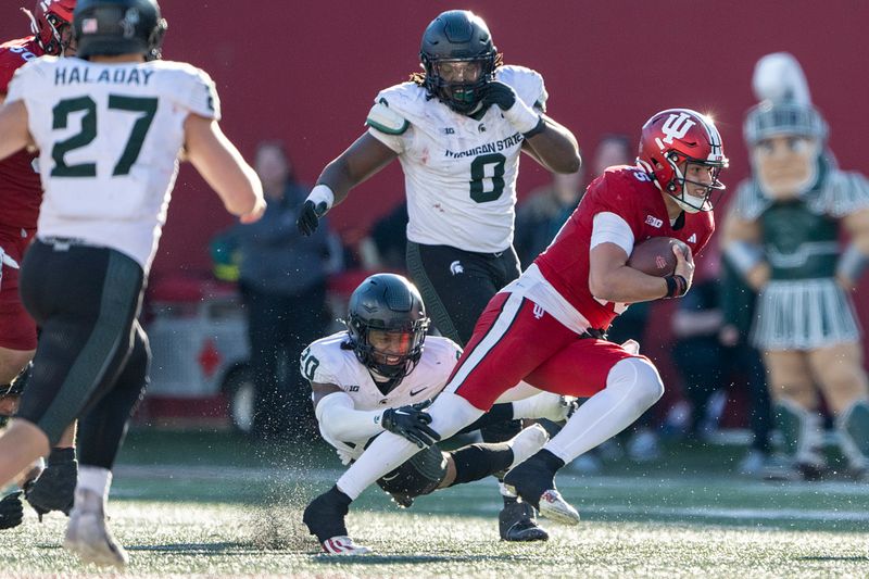 Nov 18, 2023; Bloomington, Indiana, USA; Indiana Hoosiers quarterback Brendan Sorsby (15) is tackled by Michigan State Spartans defensive back Ade Willie (20) during the second half at Memorial Stadium. Mandatory Credit: Marc Lebryk-USA TODAY Sports