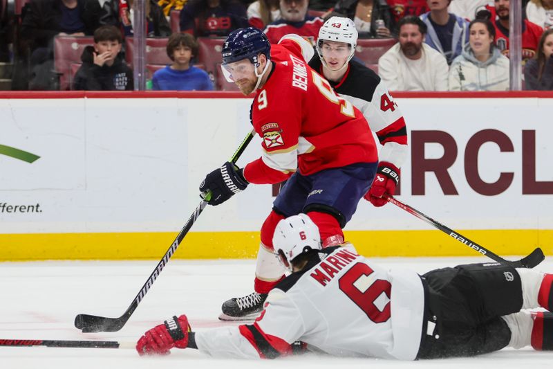 Jan 13, 2024; Sunrise, Florida, USA; Florida Panthers center Sam Bennett (9) moves the puck as New Jersey Devils defenseman John Marino (6) defends during the second period at Amerant Bank Arena. Mandatory Credit: Sam Navarro-USA TODAY Sports