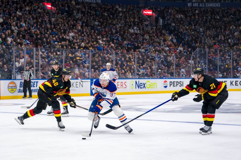 Nov 9, 2024; Vancouver, British Columbia, CAN; Edmonton Oilers forward Connor McDavid (97) drives between Vancouver Canucks forward Elias Pettersson (40) and forward Nils Hoglander (21) during the third period at Rogers Arena. Mandatory Credit: Bob Frid-Imagn Images