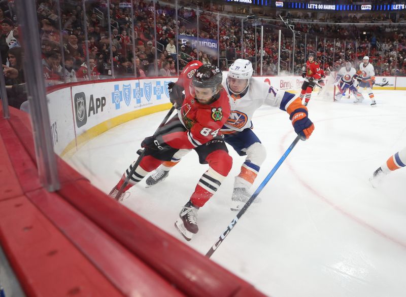 Dec 30, 2025; Chicago, Illinois, USA; Chicago Blackhawks left wing Landon Slaggert (84) and New York Islanders defenseman Tony Deangelo (77) battle for control of the puck during the first period at United Center. Mandatory Credit: Talia Sprague-Imagn Images