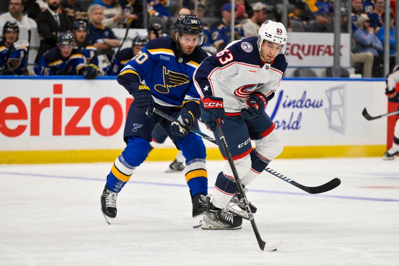 Oct 1, 2024; St. Louis, Missouri, USA;  Columbus Blue Jackets forward Jake Gaudet (63) controls the puck as St. Louis Blues left wing Brandon Saad (20) defends during the second period at Enterprise Center. Mandatory Credit: Jeff Curry-Imagn Images