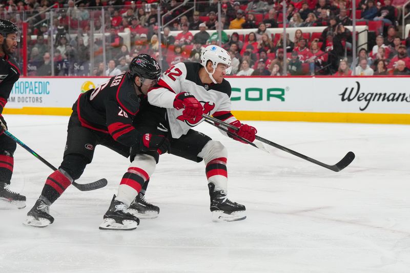 Mar 28, 2026; Raleigh, North Carolina, USA;  New Jersey Devils right wing Maxim Tsyplakov (42) gets the shot past Carolina Hurricanes defenseman Sean Walker (26) during the second period at Lenovo Center. Mandatory Credit: James Guillory-Imagn Images