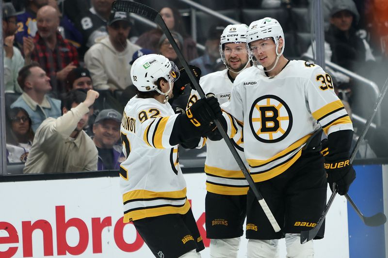 Nov 21, 2025; Los Angeles, California, USA;  Boston Bruins center Morgan Geekie (39) celebrates with center Marat Khusnutdinov (92) and defenseman Andrew Peeke (26) after scoring a goal during the third period against the Los Angeles Kings at Crypto.com Arena. Mandatory Credit: Kiyoshi Mio-Imagn Images