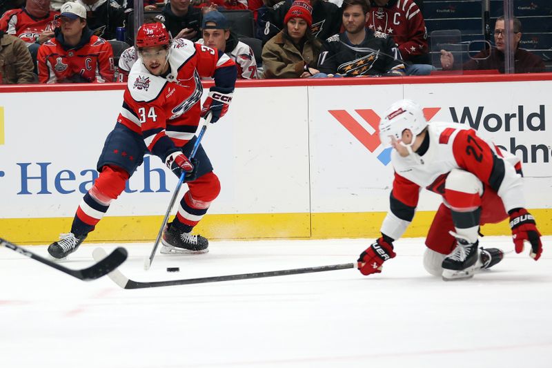 Jan 31, 2026; Washington, District of Columbia, USA; Washington Capitals right wing Justin Sourdif (34) shoots the puck past Carolina Hurricanes left wing Nikolaj Ehlers (27) during the first period at Capital One Arena. Mandatory Credit: Daniel Kucin Jr.-Imagn Images