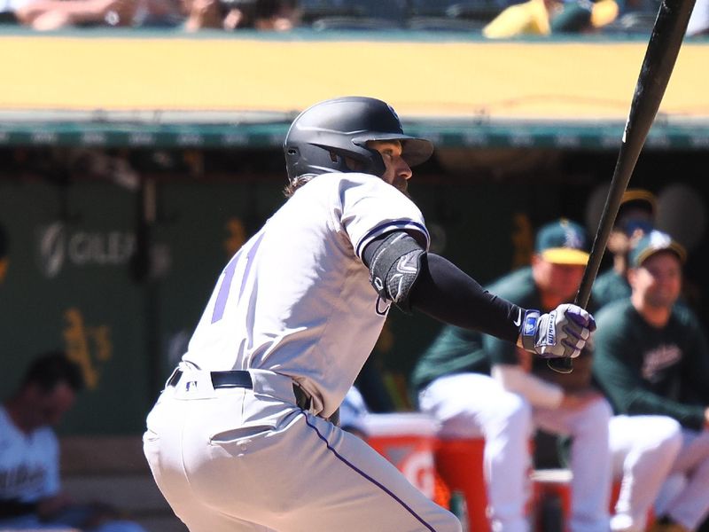 May 23, 2024; Oakland, California, USA; Colorado Rockies right fielder Jake Cave (11) hits an RBI single against the Oakland Athletics during the eleventh inning at Oakland-Alameda County Coliseum. Mandatory Credit: Kelley L Cox-USA TODAY Sports