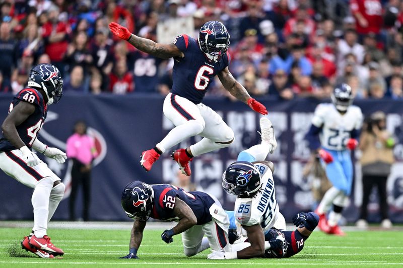 Houston Texans cornerback Kareem Jackson (22) tackles Tennessee Titans tight end Chigoziem Okonkwo (85) as linebacker Denzel Perryman (6) leaps over the pile in the fourth quarter during an NFL football game, Sunday, Dec 31, 2023, in Houston. (AP Photo/Maria Lysaker)