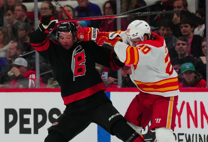 Mar 10, 2024; Raleigh, North Carolina, USA;  Calgary Flames center Blake Coleman (20) checks Carolina Hurricanes right wing Andrei Svechnikov (37) during the first period at PNC Arena. Mandatory Credit: James Guillory-USA TODAY Sports