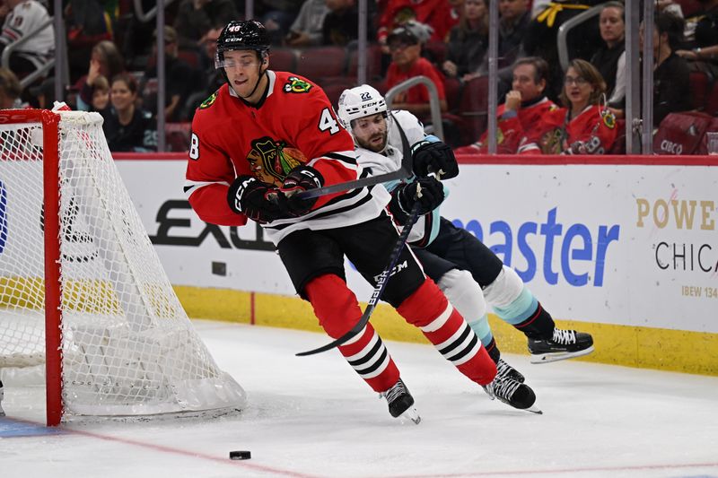 Oct 23, 2022; Chicago, Illinois, USA;  Seattle Kraken forward Oliver Bjorkstrand (22) attempts to slow down Chicago Blackhawks defenseman Filip Roos (48) who skates the puck around his net in the third period at United Center. Chicago defeated Seattle 5-4. Mandatory Credit: Jamie Sabau-USA TODAY Sports