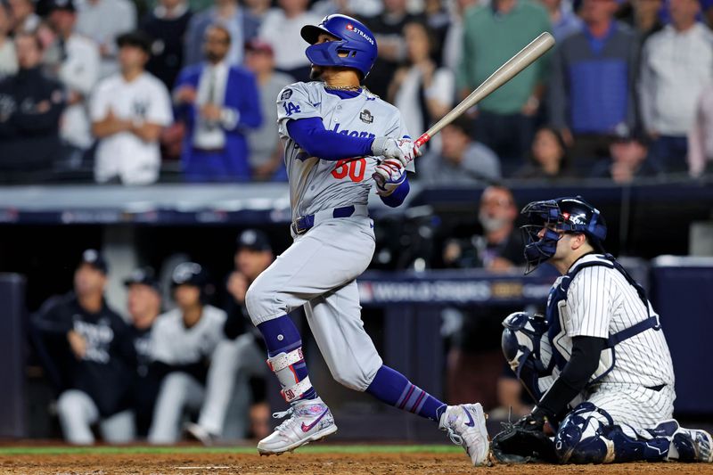 Oct 30, 2024; New York, New York, USA; Los Angeles Dodgers shortstop Mookie Betts (50) hits a sacrifice fly during the eighth inning against the New York Yankees in game four of the 2024 MLB World Series at Yankee Stadium. Mandatory Credit: Brad Penner-Imagn Images