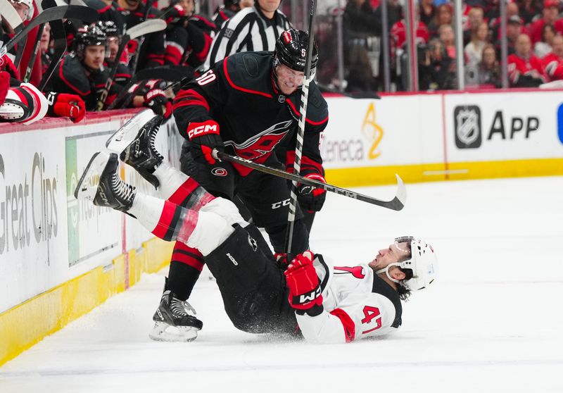Apr 29, 2025; Raleigh, North Carolina, USA; Carolina Hurricanes left wing Eric Robinson (50) checks New Jersey Devils center Paul Cotter (47) during the first period in game five of the first round of the 2025 Stanley Cup Playoffs at Lenovo Center. Mandatory Credit: James Guillory-Imagn Images