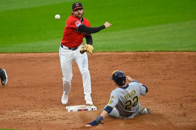 May 12, 2025; Cleveland, Ohio, USA; Cleveland Guardians second baseman Daniel Schneemann (10) turns a double play beside Milwaukee Brewers designated hitter Christian Yelich (22) in the fifth inning at Progressive Field. Mandatory Credit: David Richard-Imagn Images