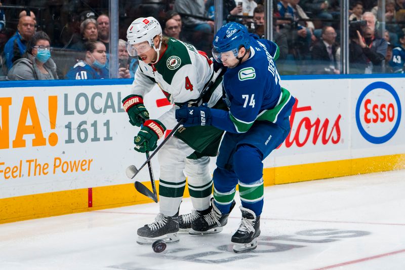 Apr 12, 2025; Vancouver, British Columbia, CAN; Vancouver Canucks forward Jake DeBrusk (74) checks Minnesota Wild defenseman Jon Merrill (4) in the second period at Rogers Arena. Mandatory Credit: Bob Frid-Imagn Images