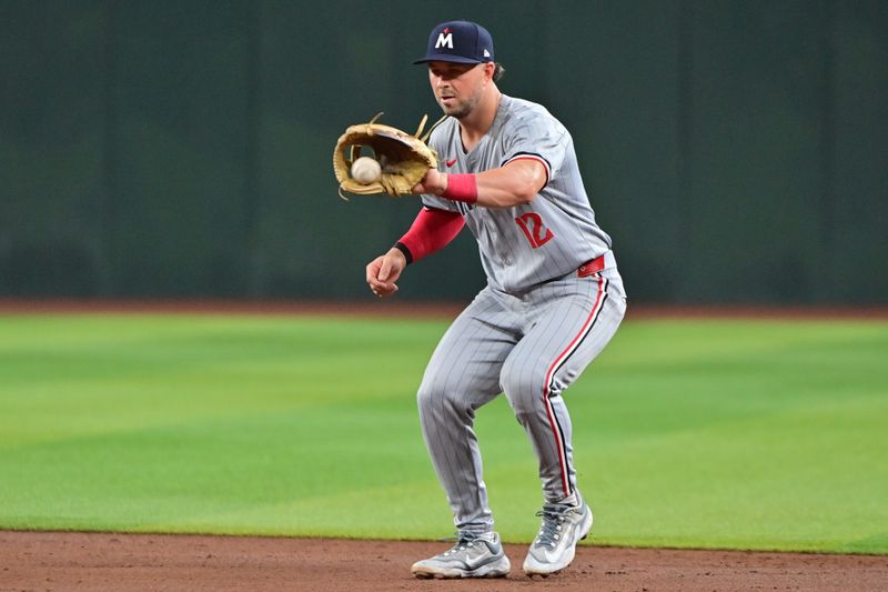 Jun 27, 2024; Phoenix, Arizona, USA;  Minnesota Twins second base Kyle Farmer (12) fields a ground ball in the third inning against the Arizona Diamondbacks at Chase Field. Mandatory Credit: Matt Kartozian-USA TODAY Sports