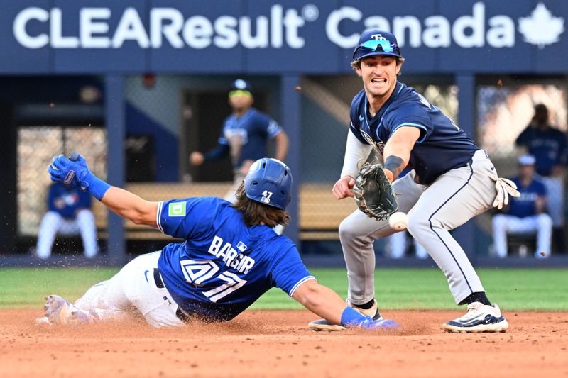 Sep 28, 2025; Toronto, Ontario, CAN;  Toronto Blue Jays third baseman Addison Barger (47) slides into second base with a double as the ball bounces past Tampa Bay Rays shortstop Carson Williams (7) in the fifth inning at Rogers Centre. Mandatory Credit: Dan Hamilton-Imagn Images