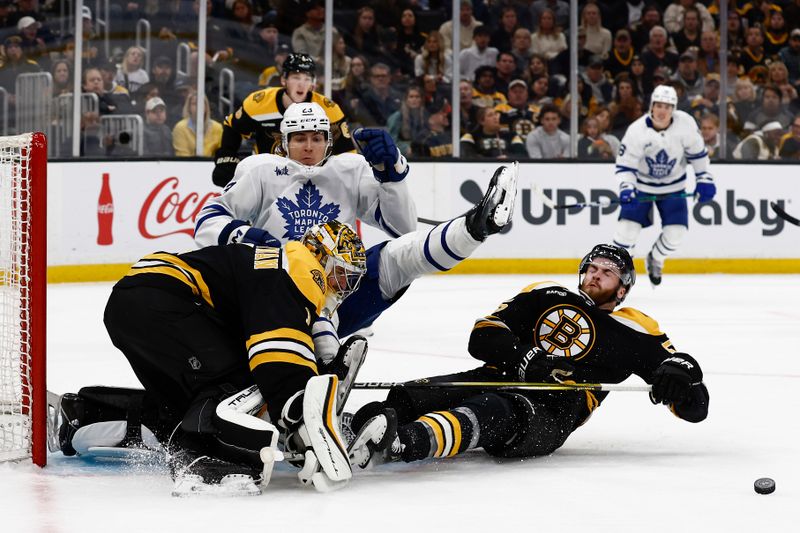 Oct 26, 2024; Boston, Massachusetts, USA; Toronto Maple Leafs left wing Matthew Knies (23) is upended by Boston Bruins right wing Justin Brazeau (55) battling for a rebound in front of goaltender Jeremy Swayman (1) during the second period at TD Garden. Mandatory Credit: Winslow Townson-Imagn Images