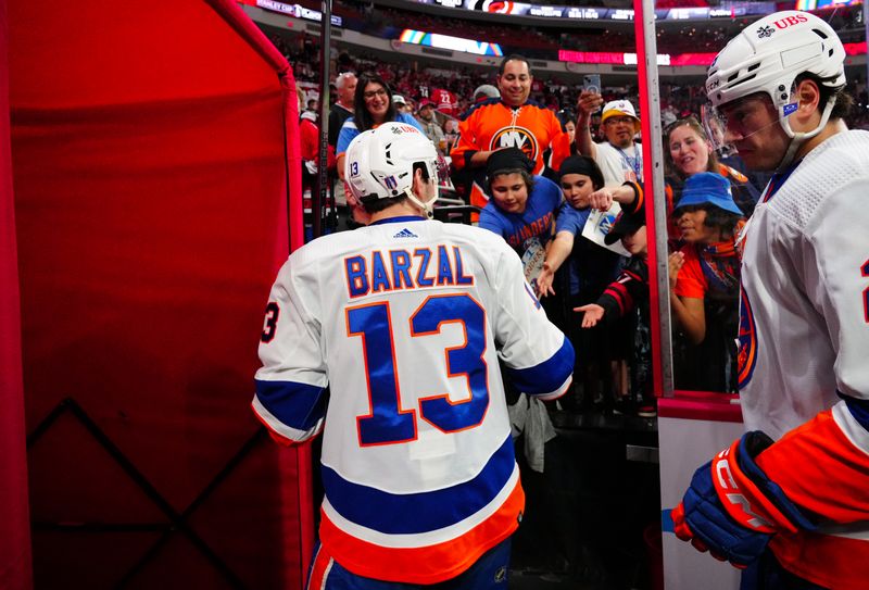 Apr 20, 2024; Raleigh, North Carolina, USA; New York Islanders center Mathew Barzal (13) hands a puck to a fan as he comes off the ice after the warmups against the Carolina Hurricanes in game one of the first round of the 2024 Stanley Cup Playoffs at PNC Arena. Mandatory Credit: James Guillory-USA TODAY Sports