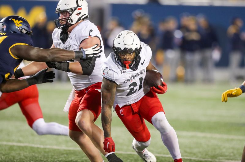 Nov 18, 2023; Morgantown, West Virginia, USA; Cincinnati Bearcats running back Corey Kiner (21) runs the ball during the fourth quarter against the West Virginia Mountaineers at Mountaineer Field at Milan Puskar Stadium. Mandatory Credit: Ben Queen-USA TODAY Sports